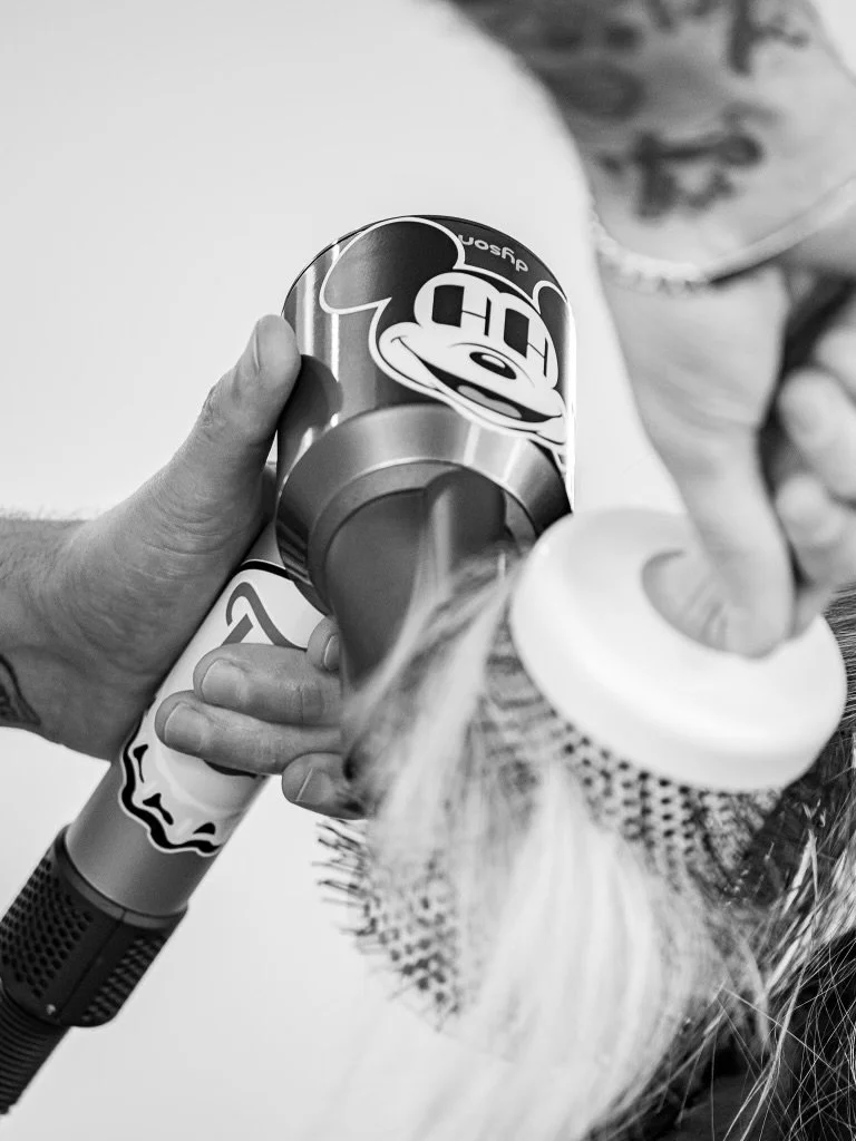 A stylist blow drying hair at Hair House ATX